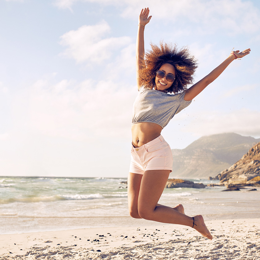 Woman on beach jumping for joy