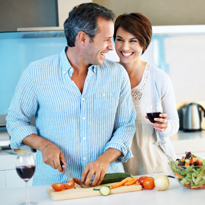 Smiling couple preparing a meal with wine