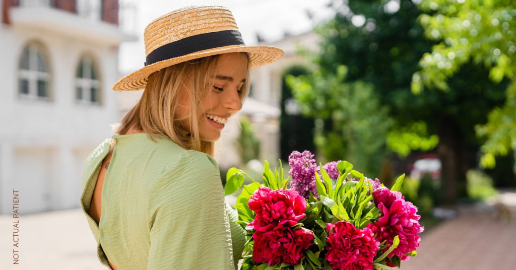 Woman with flowers smiling looking over shoulder (model)