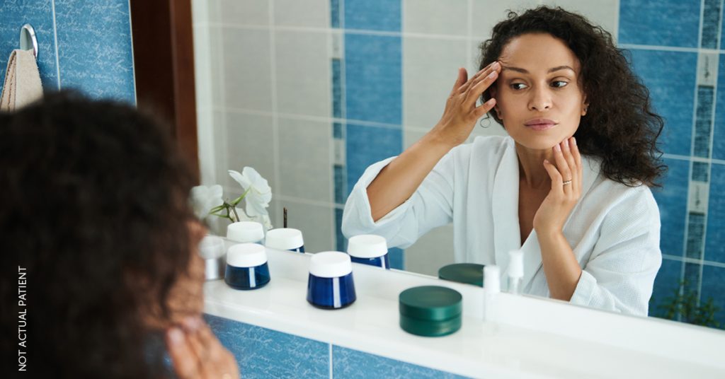 Woman looking in mirror lifting up eye (not an actual patient)