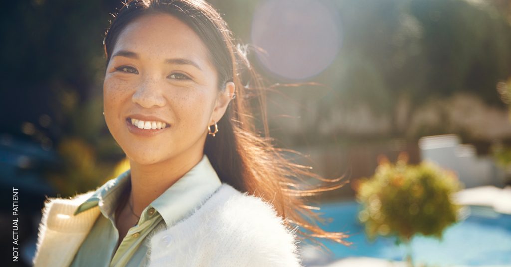 Beautiful woman standing outside on a sunny day and smiling at the camera. (Model)