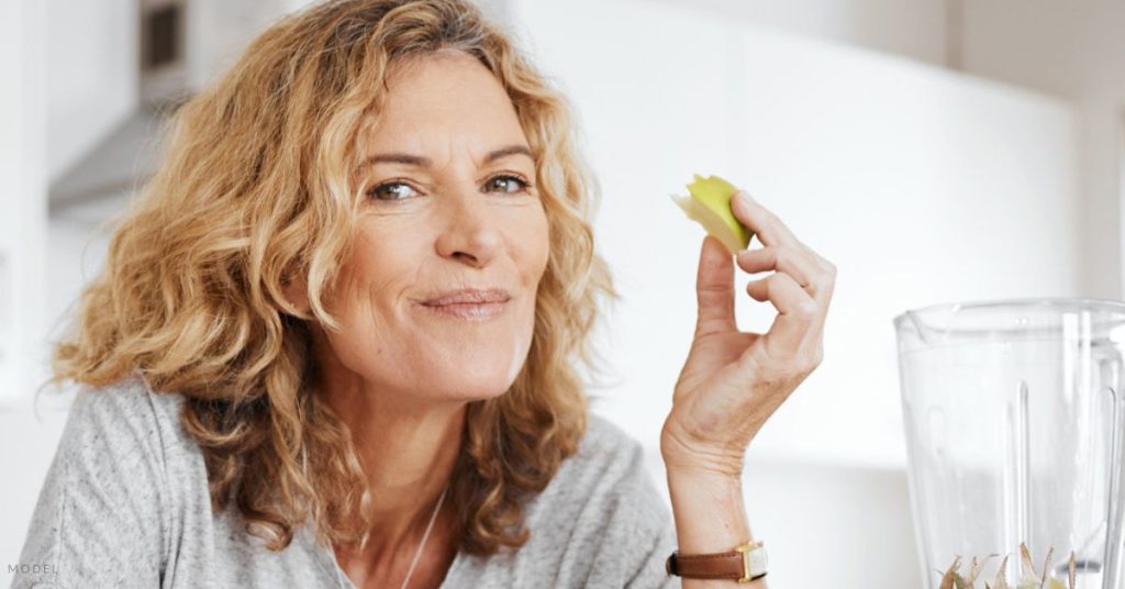 A middle-aged woman happily enjoying some fruit (MODEL)