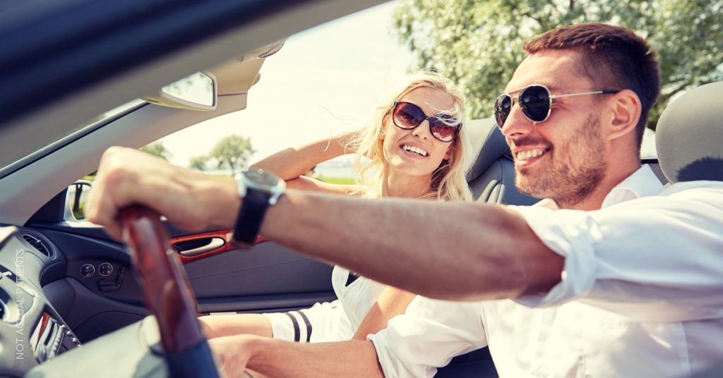 Smiling man and woman driving in a convertible vehicle (models)