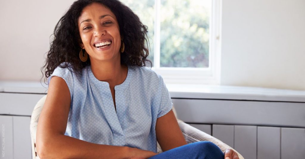 A woman sitting in chair at home after abdominal wall reconstruction for hernia repair. (Model)