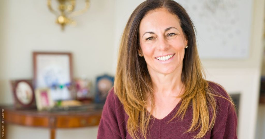Woman with long brown hair smiling at the camera (model)